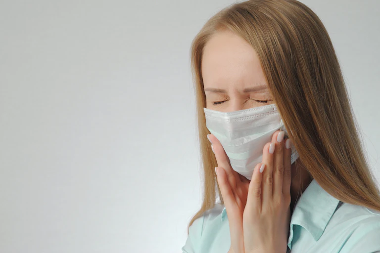 Mujer con mascarilla doliéndose de la mandíbula