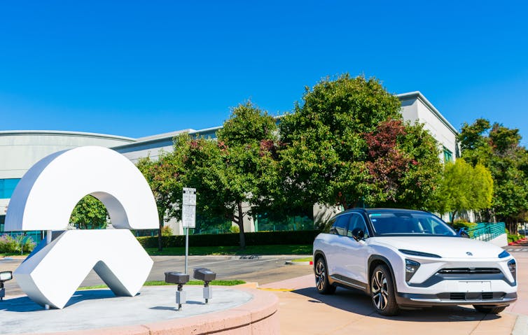 A NIO car parked outside next to a statue of the firm's logo