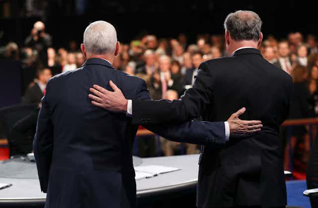 Mike Pence and Tim Kaine stand holding each other's backs at a debate
