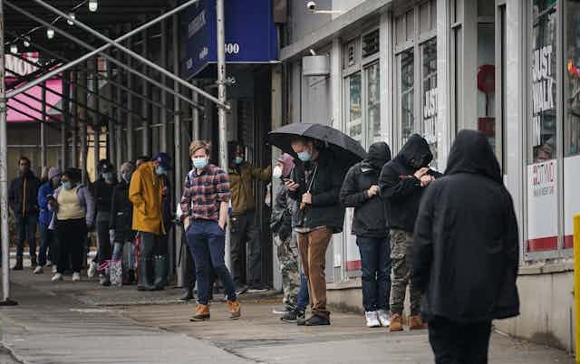 People wearing masks wait in line to get a coronavirus test in New York City.
