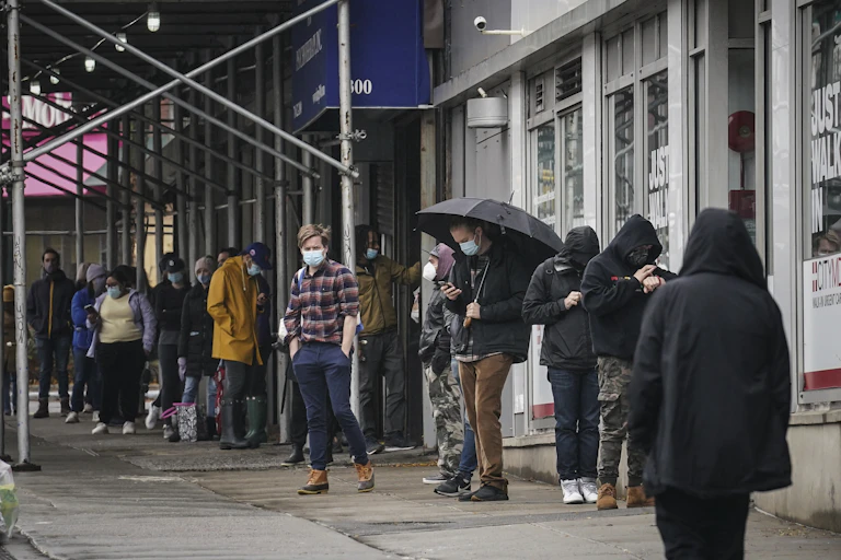 People wearing masks wait in line to get a coronavirus test in New York City.