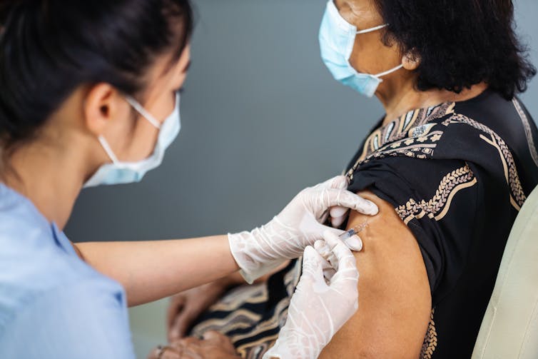 A woman receives a vaccination from a health-care worker.