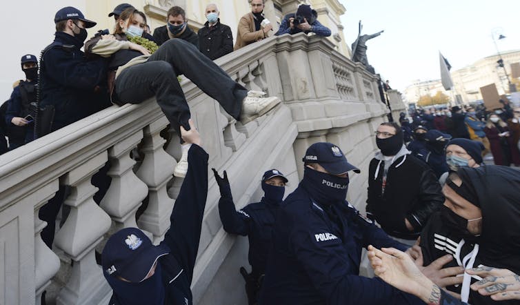Members of a far-right organization and police remove women from a church where they were protesting church support for tightening Poland’s already restrictive abortion law in Warsaw, Poland, on Oct. 25, 2020