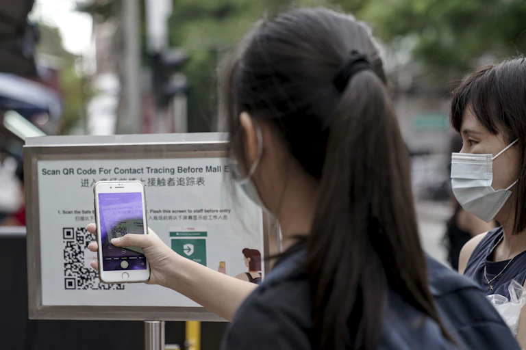 Person scanning QR code before entering a mall