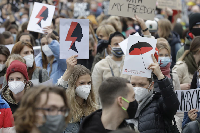 Women carrying signs march in the Warsaw streets.