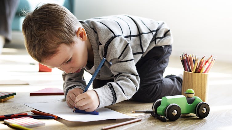 A boy draws on paper.