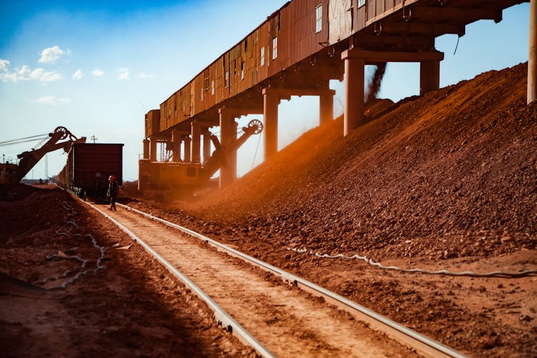 Machines load a train cart with minerals in an open-cast bauxite mine.