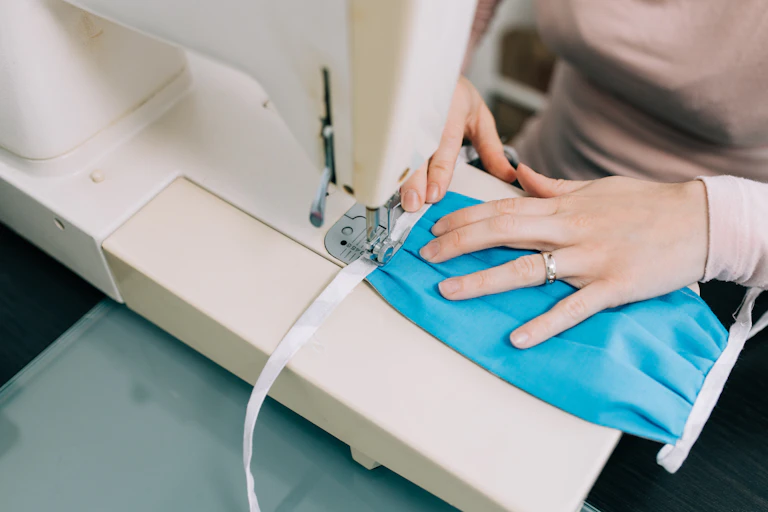 A woman creating a face mask using a sewing machine