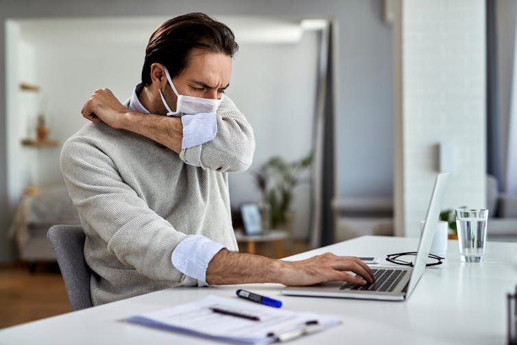 A man wearing a mask coughing