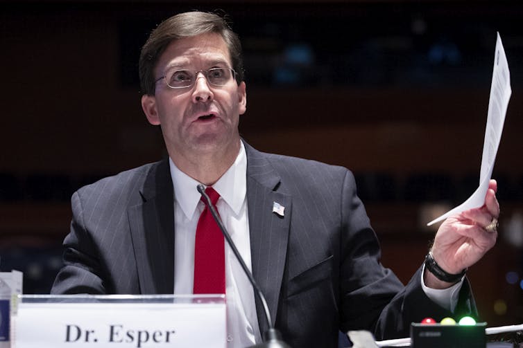 Esper testifying in Congress, holding a piece of paper