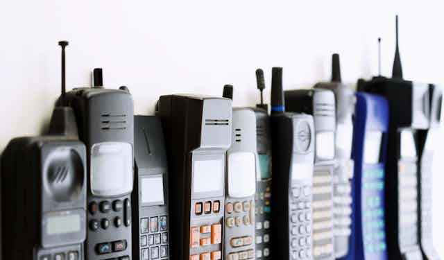 A row of old cellular phones from the 80s and 90s.