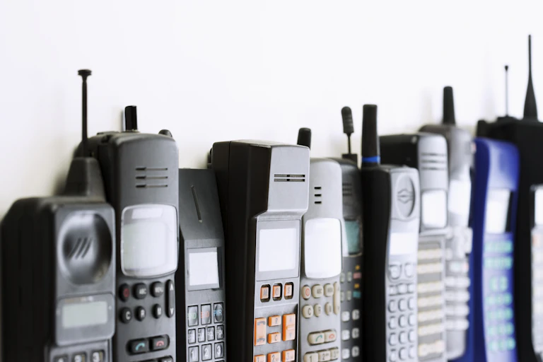 A row of old cellular phones from the 80s and 90s.