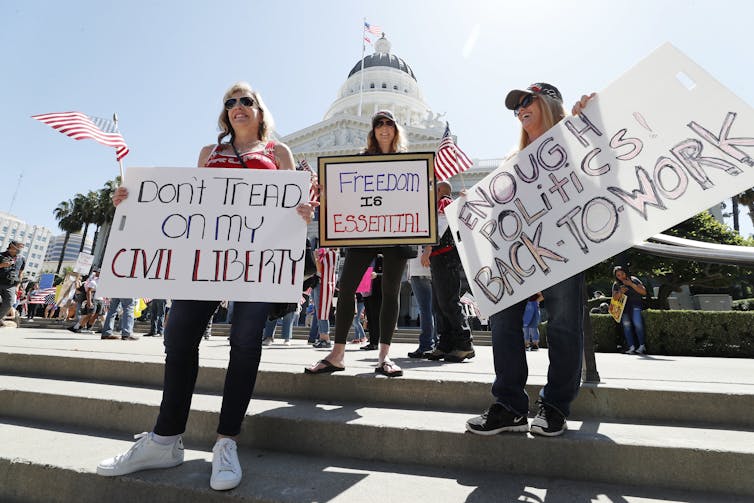 People holding signs protesting coronavirus restrictions in the USA