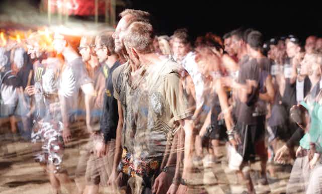 Men look blurred at a public event.