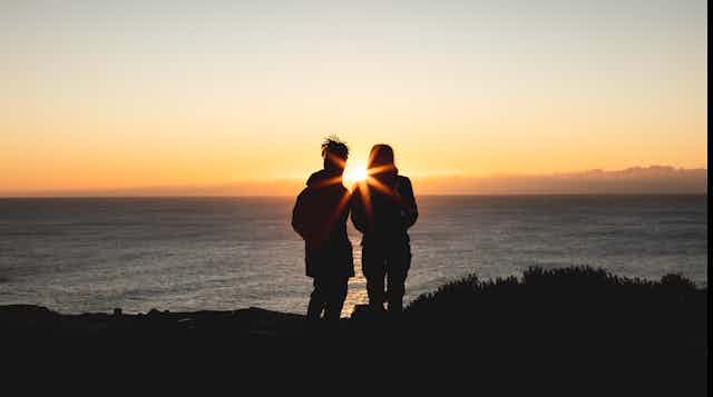 Couple watching the Sun rise over the ocean