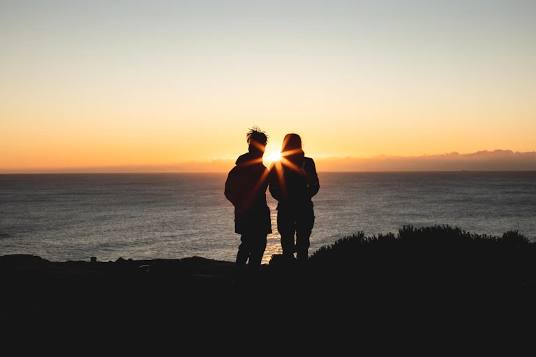 Couple watching the Sun rise over the ocean