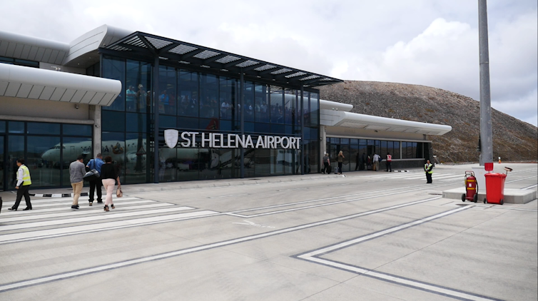 The concrete approach and glass front wall of an airport reception area.