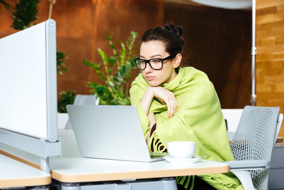Woman wrapped in a blanket while using her laptop.