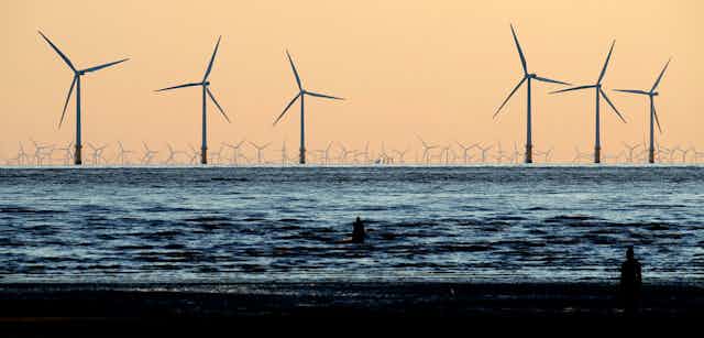 Wind turbines at sea, viewed from a beach