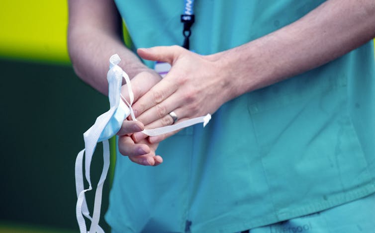 A woman's hands holding a surgical mask.