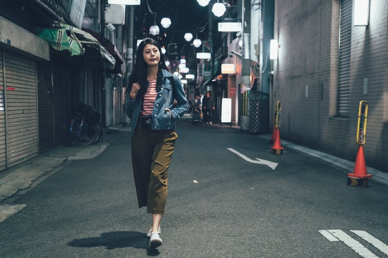 A woman walks alone in a street.