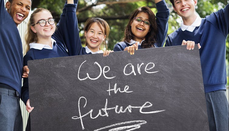 Children in uniform hold sign with caption, 'We are the future'
