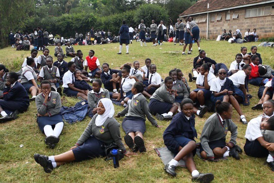 Girl students seated on the grass in their school compound.