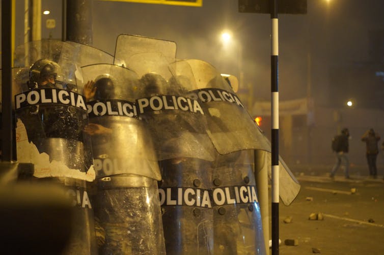 Los policías se cubren con sus escudos durante un enfrentamiento con manifestantes durante la protesta contra la decisión del Congreso de destituir al expresidente Martín Vizcarra. Lima, 12 de noviembre de 2020- Shutterstock / Joseph Everth