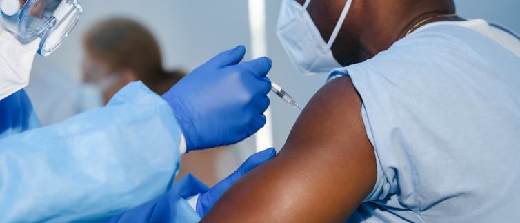 A Black man receiving an injection in his arm