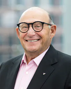 A smiling bald man wearing glasses