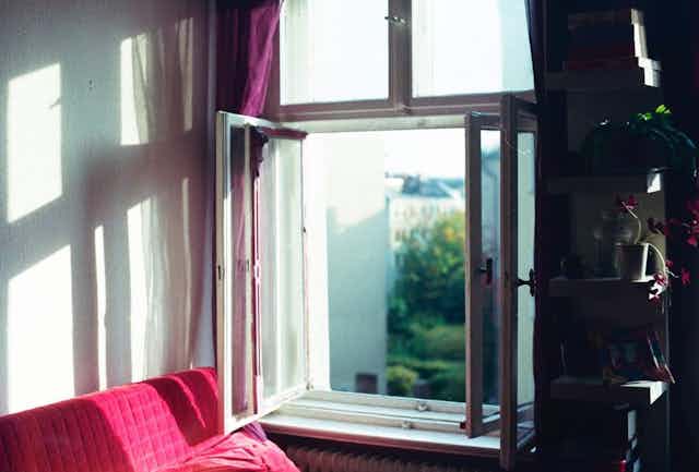 An open window next to a red couch.