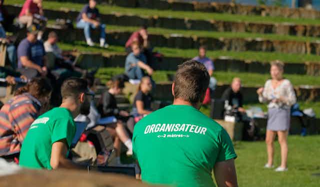 The back of  a young man in a t-shirt in an outdoor ampitheatre.