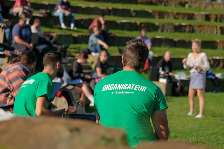 The back of a young man in a t-shirt in an outdoor ampitheatre.