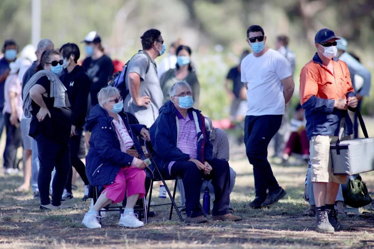 People queuing outside waiting for COVID testing, wearing masks