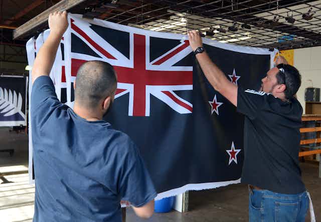 Two men holding up a New Zealand flag.