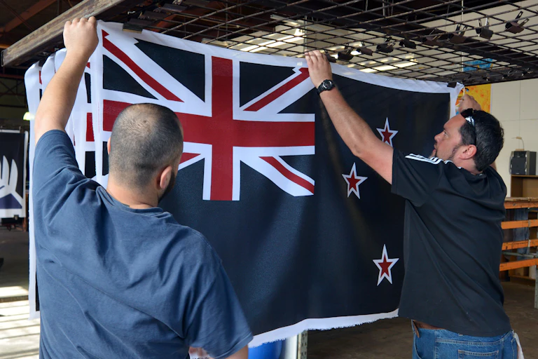 Two men holding up a New Zealand flag.