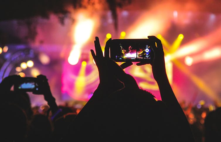 Crowd at concert holds phones up high to take photos.