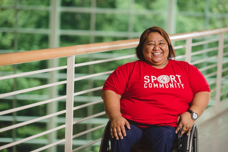 Woman in wheelchair smiling with hands in her lap.