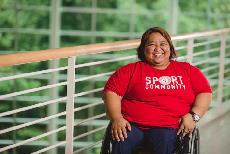 Woman in wheelchair smiling with hands in her lap.
