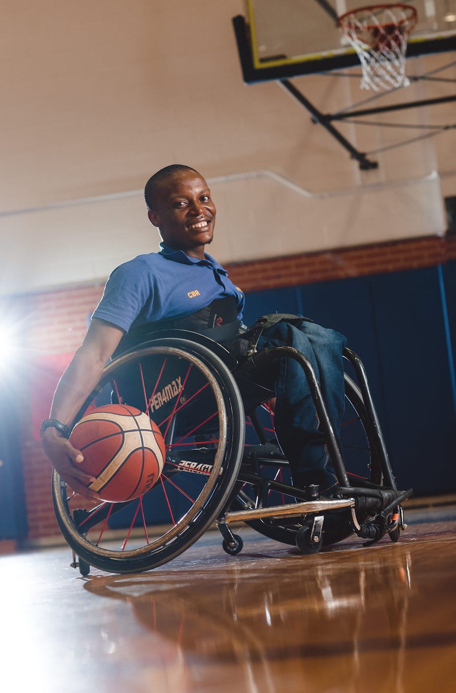 Man in sports wheelchair holding a basketball.