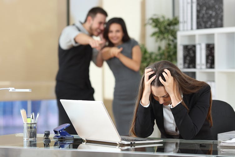 Image of a woman being bullied by colleagues.