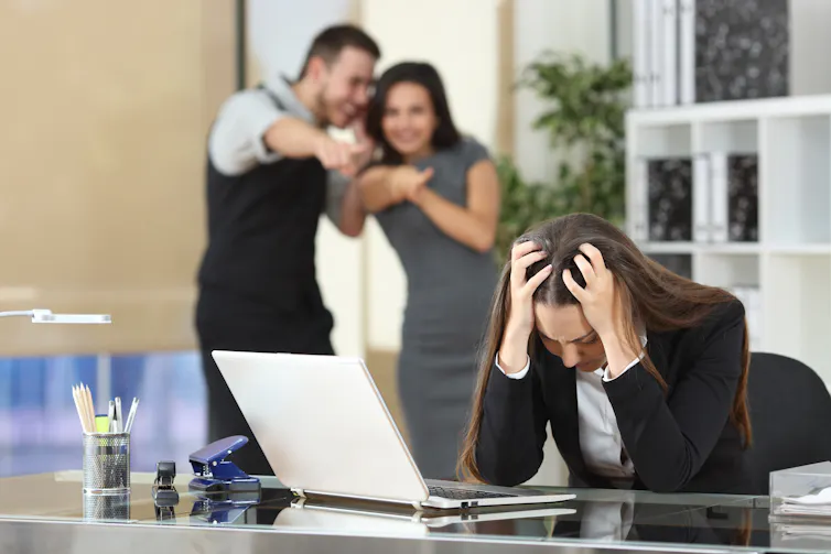 Image of a woman being bullied by colleagues.