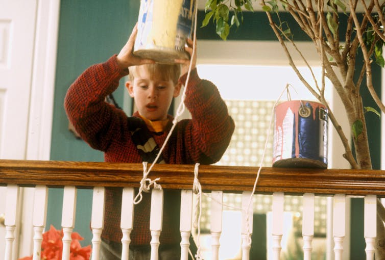 Kevin holds paint cans over the banister.