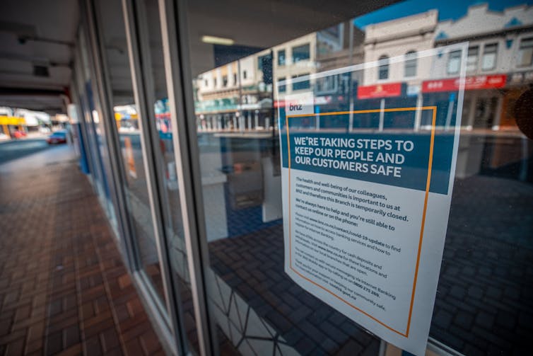 A sign in a shop window uring people to take COVID safe precautions.