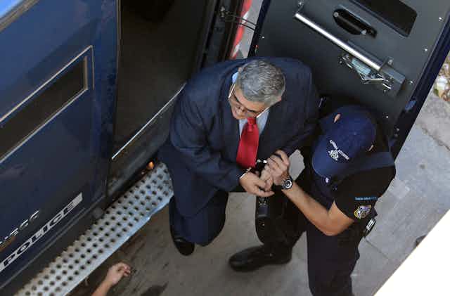 Leader of far-right Golden Dawn Party Nikos Michaloliakos leaves a police van in handcuffs.
