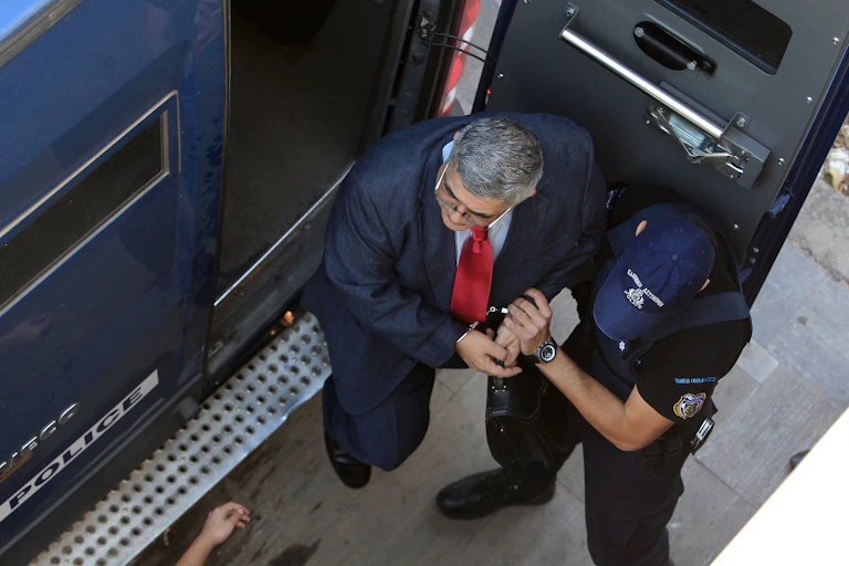 Leader of far-right Golden Dawn Party Nikos Michaloliakos leaves a police van in handcuffs.