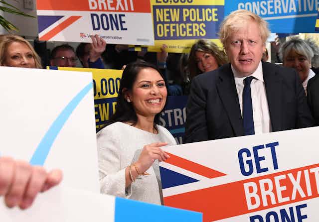 Priti Patel and Boris Johnson holding a 'get Brexit done' sign. 
