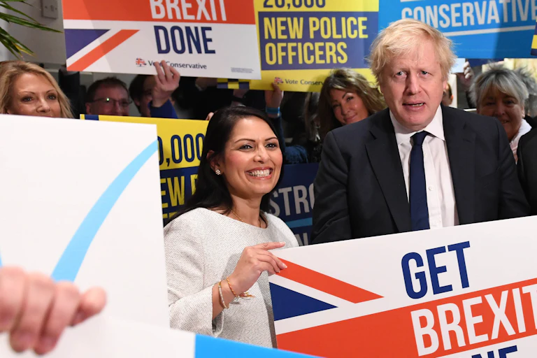 Priti Patel and Boris Johnson holding a 'get Brexit done' sign.