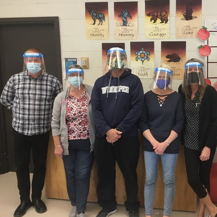 Educational assistants standing wearing face shields.