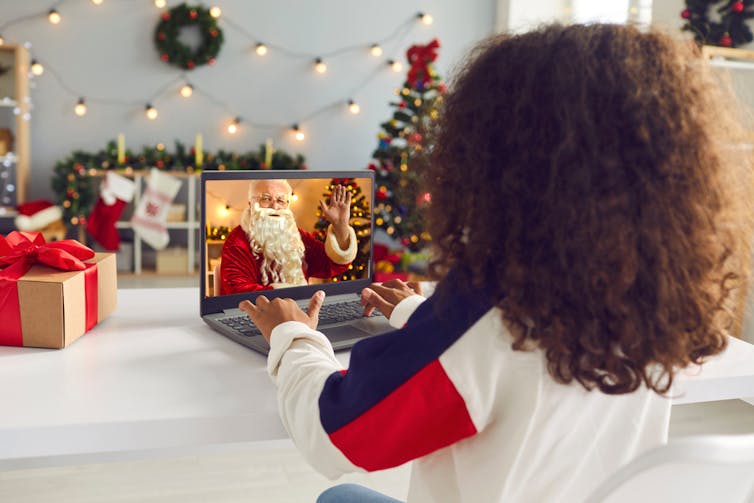Child looks at Santa on a laptop